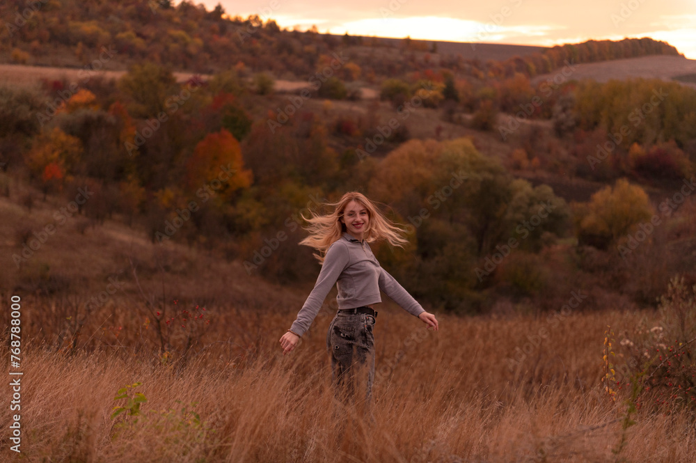 Young attractive blonde woman standing on the hill at sunset Young attractive blonde woman standing on the hill at sunset