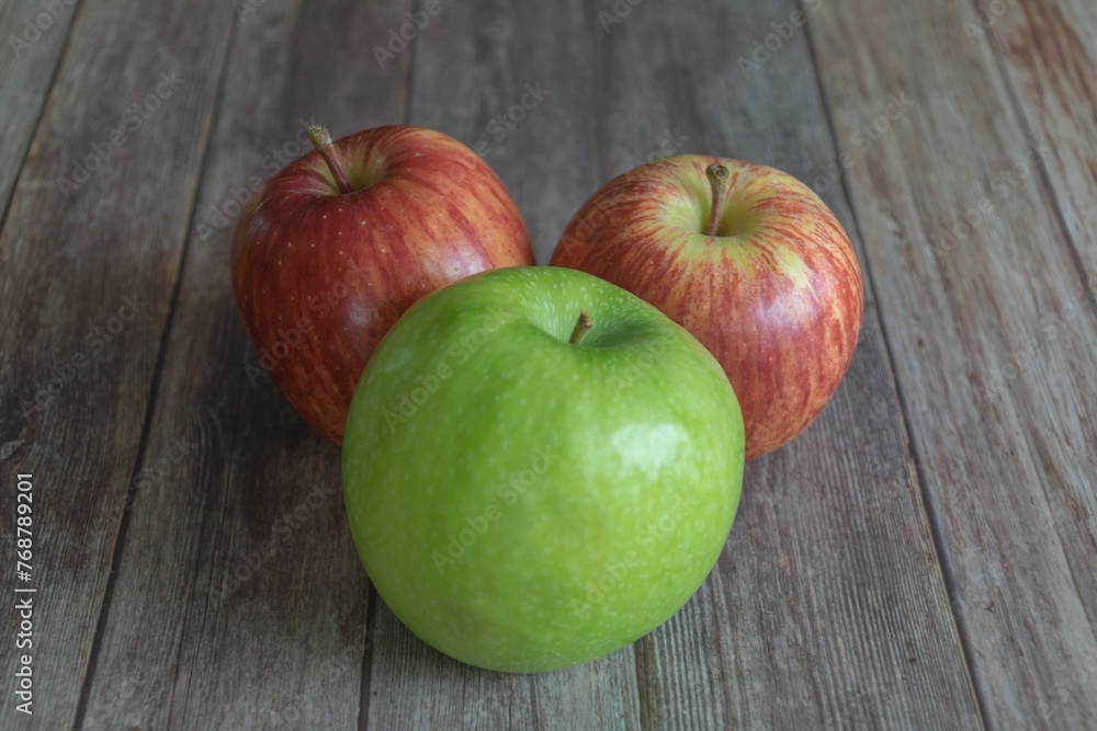 Two red and one green apple on a wooden table Two red and one green apple on a wooden table