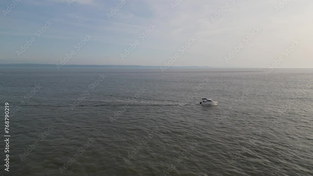Aerial video of a boat floating next to the shore on a sunny day Aerial video of a boat floating next to the shore on a sunny day