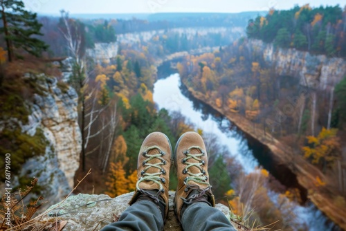 Perched above a forested gorge, a hiker's feet point towards an autumn-kissed valley, reflecting a moment of peace and the silent beauty of the changing seasons.