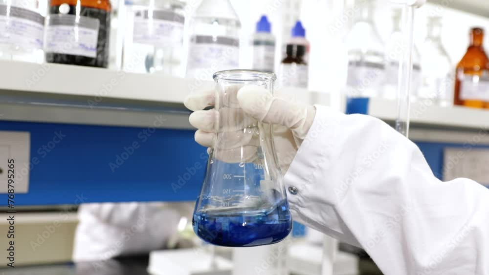 scientist mixing chemicals in flask. conducting experiment science experiment in a beaker flask titration with colorful blue chemical liquid in laboratory with medical drug equipment scientist mixing chemicals in flask. conducting experiment science experiment in a beaker flask titration with colorful blue chemical liquid in laboratory with medical drug equipment