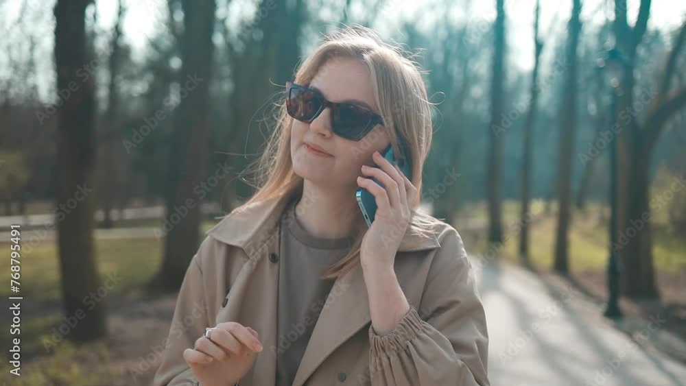 Casual happy woman on the phone in a park sitting on a bench. Portrait of beautiful young woman in urban background talking on phone. High quality FullHD footage Casual happy woman on the phone in a park sitting on a bench. Portrait of beautiful young woman in urban background talking on phone. High quality FullHD footage