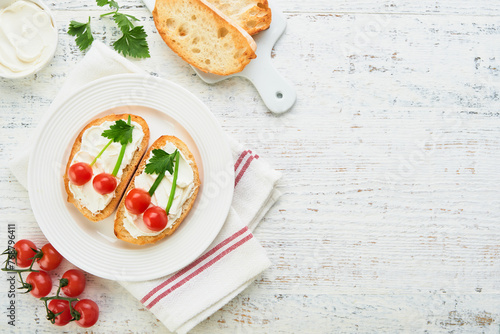 Funny toast in shape of ripe cherries sandwich with cream cheese, bread, cherry tomato, onion and parsley. Food art idea for kids food. Creative breakfast, top view, copy space