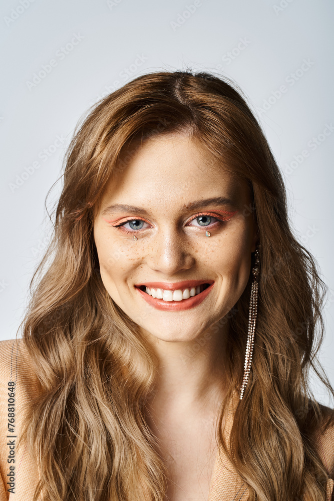 Beauty portrait of smiling young woman with face jewels makeup on grey background Beauty portrait of smiling young woman with face jewels makeup on grey background