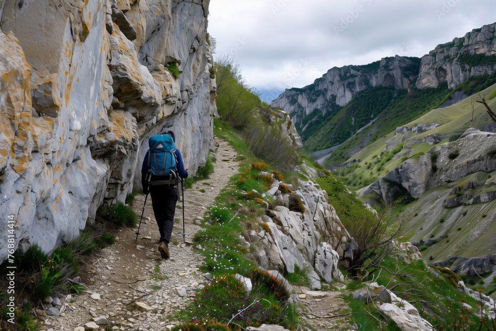 Fototapeta premium hiker navigating a narrow mountain trail with caution