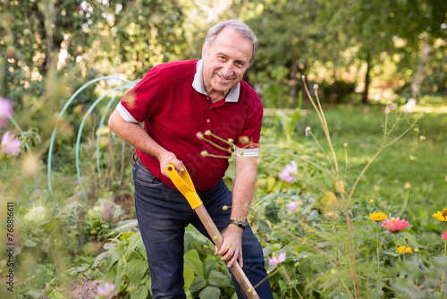 Portrait of an mature man with shovel in backyard of country house