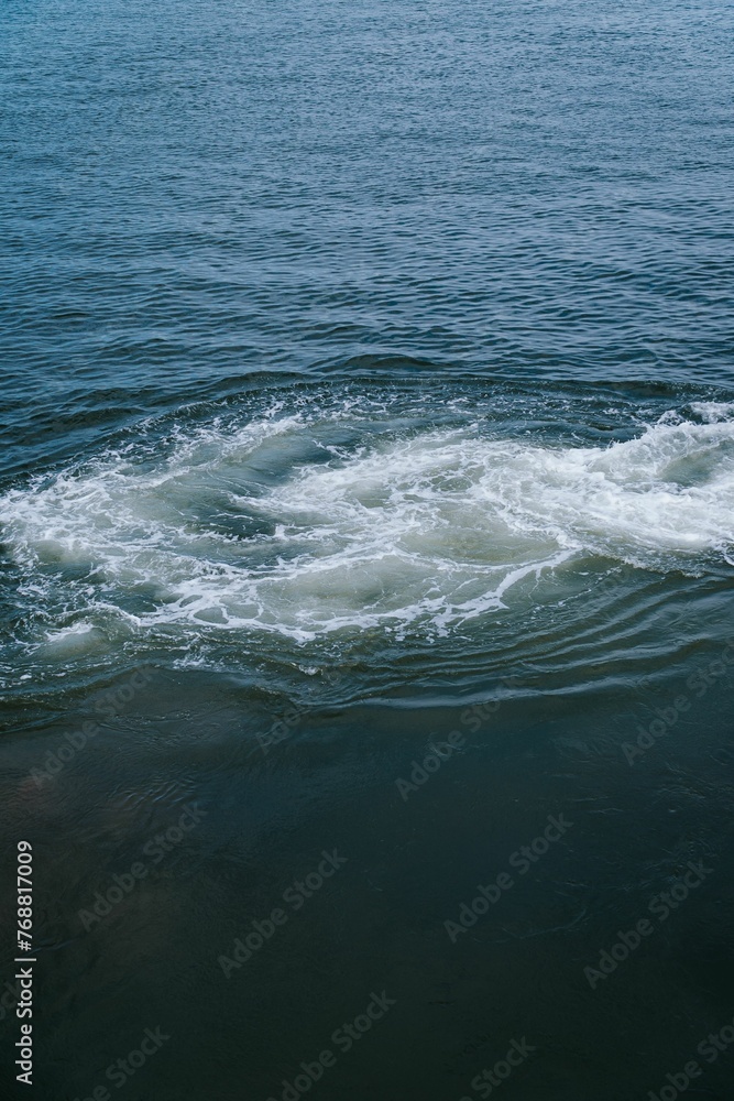 Vertical shot of foamy splashes in the water