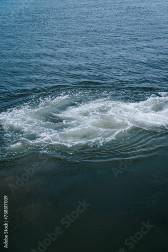 Vertical shot of foamy splashes in the water © Wirestock