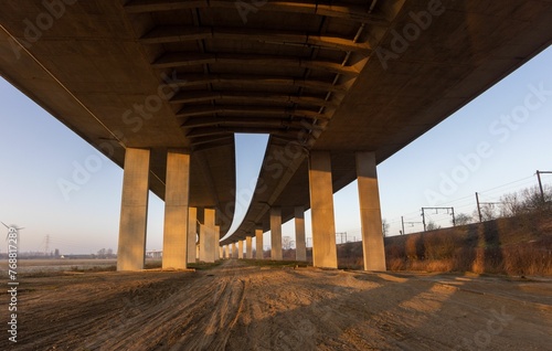 Big pillars on a road on a sunny day with windmills in the background