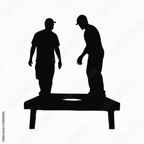 Two people sitting on a cornhole game board