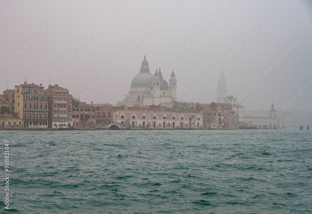 Skyline of Venice on a foggy day with Santa Maria della Salute in the foreground.