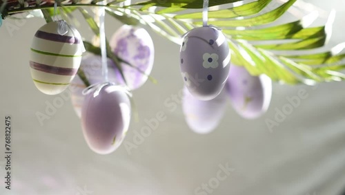 decorative Easter eggs of lilac color hanging on a palm tree branch photo