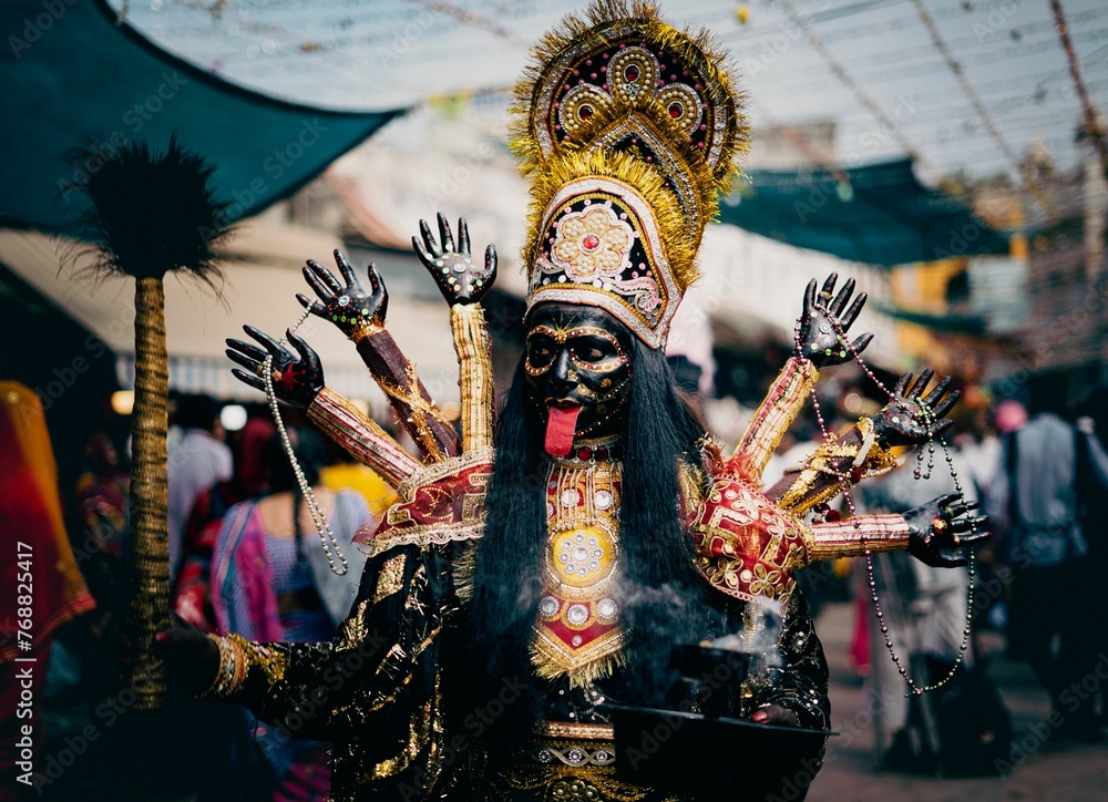 Man wearing a black and gold costume stands in a crowd of people at Mella festival in India