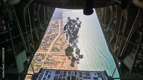 PALESTINE - 3.12.2024 - Parachutes carry airdrop supplies down from a USAF aircraft to a coastal area of Palestine. photo