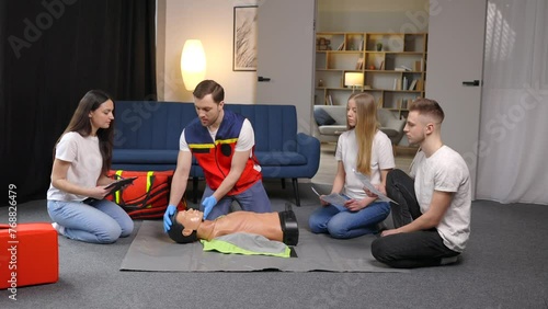 Young doctor doing cardiopulmonary resuscitation to mannequin in class. Medical team using bag valve oxygen mask rescuing unconscious people