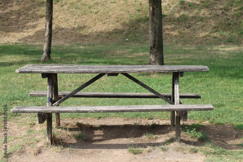 an old picnic bench in the middle of a green grass covered field