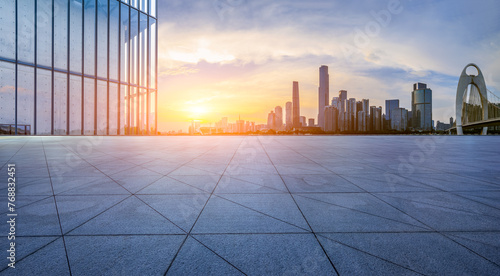 Empty square floor and glass wall with modern city buildings at sunset in Guangzhou. Panoramic view.