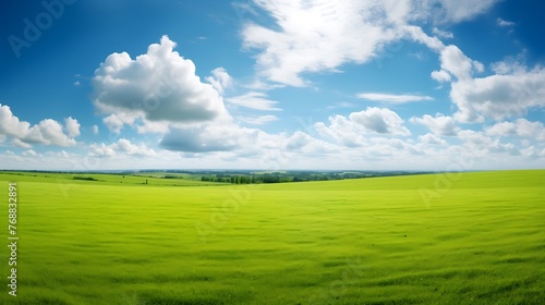 Beautiful natural scenic panorama green field of cut grass into and blue sky with clouds on horizon. Perfect green lawn on summer sunny day.