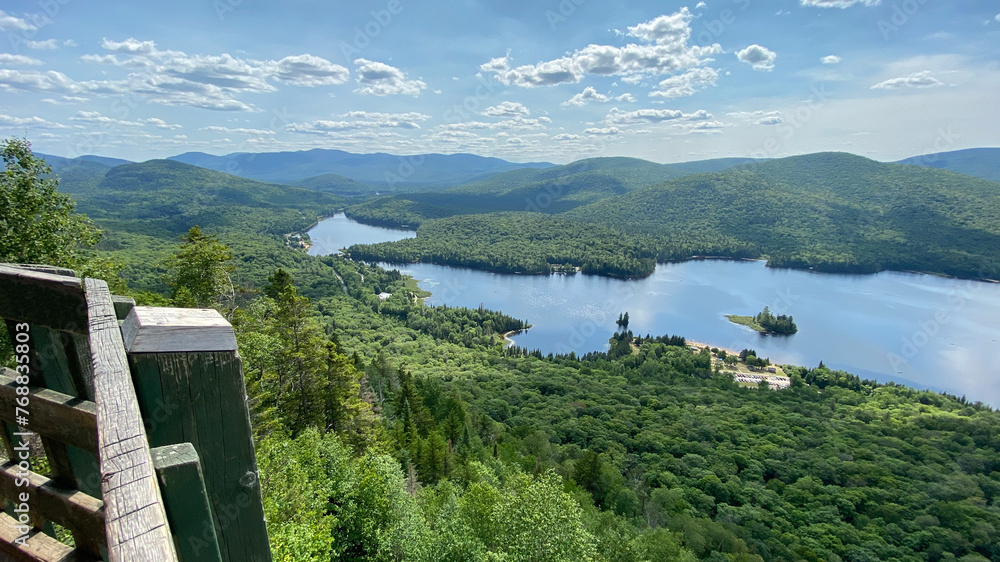 Naklejka premium Lake and mountains from a belvedere. High viewpoint of a valley in the mountains. Landscape of a river at the top of a mountain. Lookout point from a forest hike.