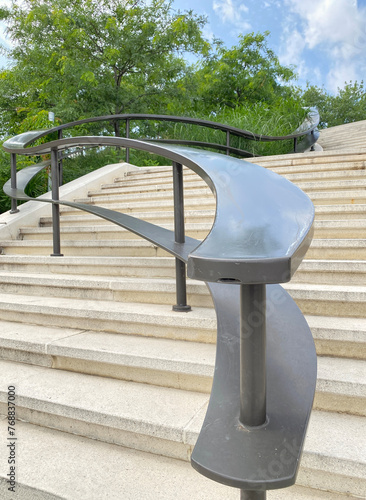 Undulating outdoor metal staircase railing. Stairs in a public park. Concrete stairway in a city.
