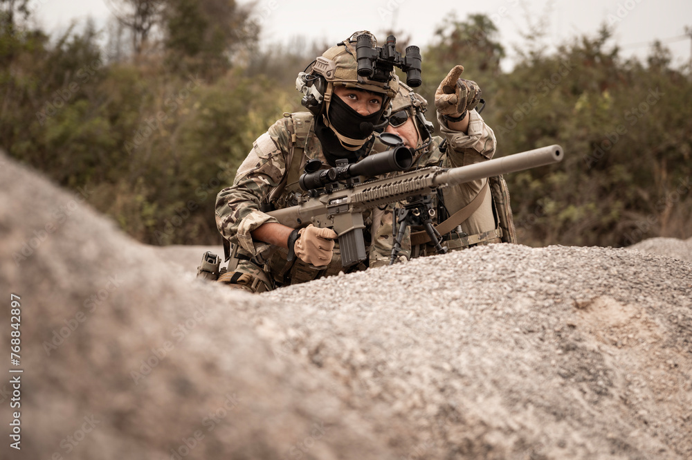 Soldiers in camouflage uniforms aiming with their rifles.ready to fire during military operation in the desert , soldiers training in a military operation Soldiers in camouflage uniforms aiming with their rifles.ready to fire during military operation in the desert , soldiers training in a military operation
