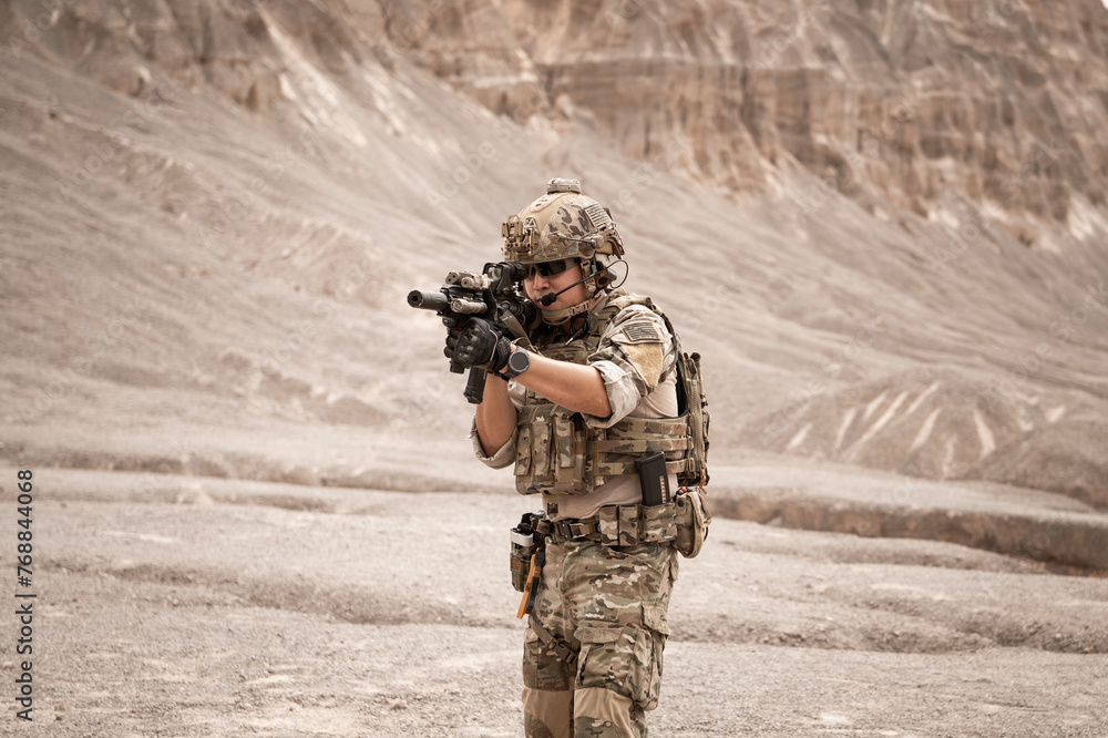 Fototapeta premium Soldiers in camouflage uniforms aiming with their rifles.ready to fire during military operation in the desert , soldiers training in a military operation