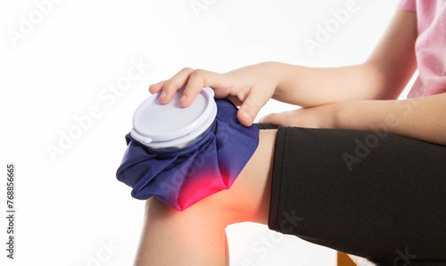 A girl applies a blue medical bag with ice to her knee joint for a knee injury. Local cryotherapy. Pain relief with cold, close-up