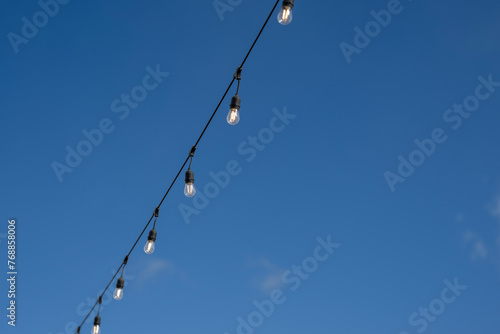 Party lights in front of a blue sky with clouds
