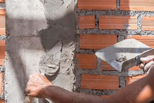Hand plaster plastering with trowel wet cement wall brick masonry background construction site  © Nature Peaceful 