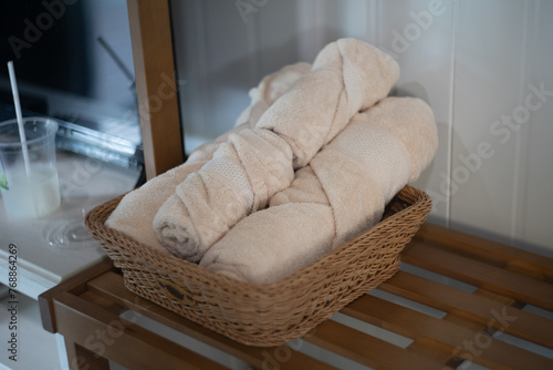 A wicker basket overflowing with fresh bread sits on a clean wooden table in a luxurious hotel room