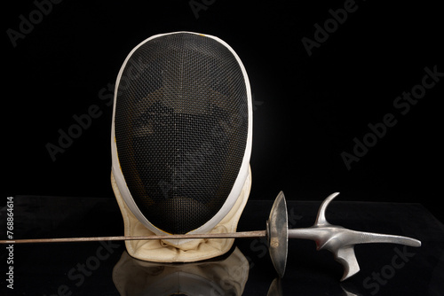 Front view of fencing sport mask and foil on black background photo