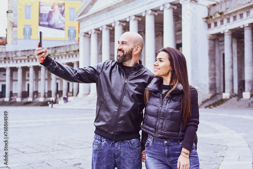 Happy smiling beautiful  Tourists  couple traveling at  Naples Italy, poses and making photos  in front of  Piazza del Plebiscito , Italy.Concept of Italian gastronomy and travel. Italian couple  © Striker777