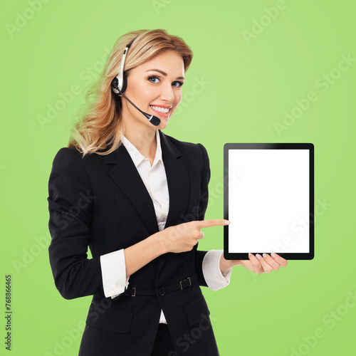 Portrait of smile businesswoman showing pointing tablet pc, touchpad, white blank screen with ad place, isolated against studio green wall background. Confident beautiful business woman