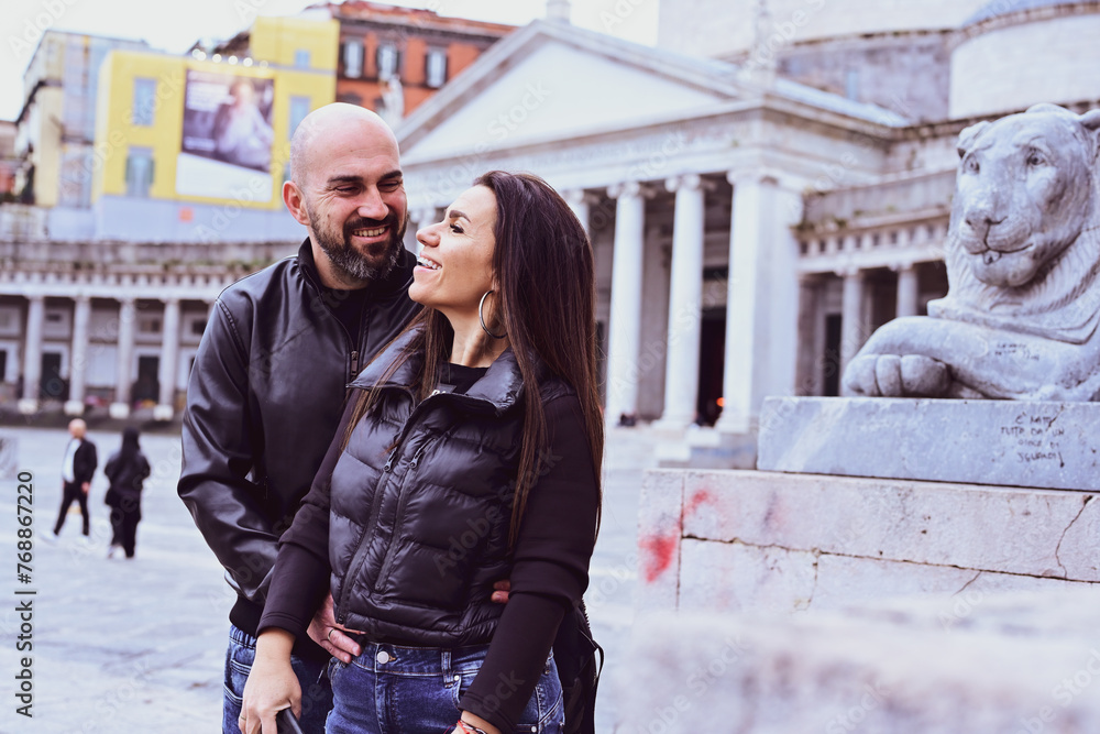 Happy smiling beautiful Tourists couple traveling at Naples Italy, poses and making photos in front of Piazza del Plebiscito , Italy.Concept of Italian gastronomy and travel. Italian couple Happy smiling beautiful Tourists couple traveling at Naples Italy, poses and making photos in front of Piazza del Plebiscito , Italy.Concept of Italian gastronomy and travel. Italian couple