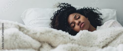Young black woman sleeping alone in bed with cozy blanket photo
