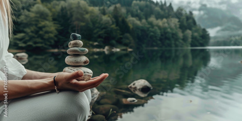 Woman holding balancing stones on the lake shore. Meditating, yoga, harmony in nature