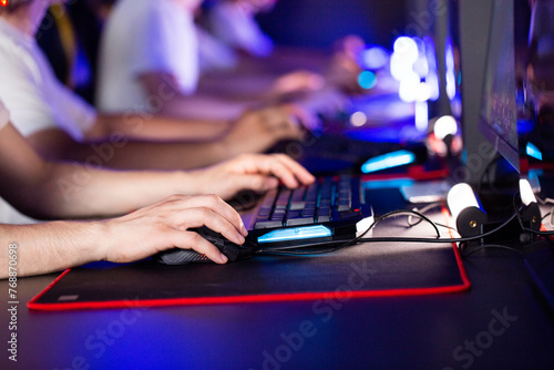 The hands of players who press buttons on the keyboard and buttons on the optical mouse in the computer club. Online gaming tournament concept, close-up photo