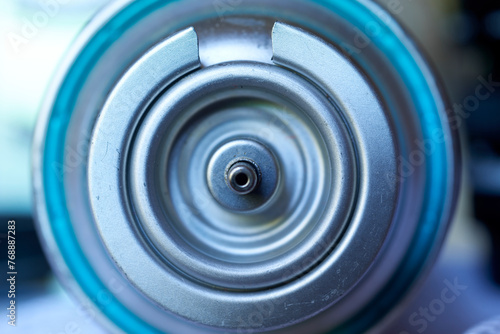 A close-up view of a valve on a camping gas cylinder, highlighting the metallic construction and the detailed design elements such as concentric circles