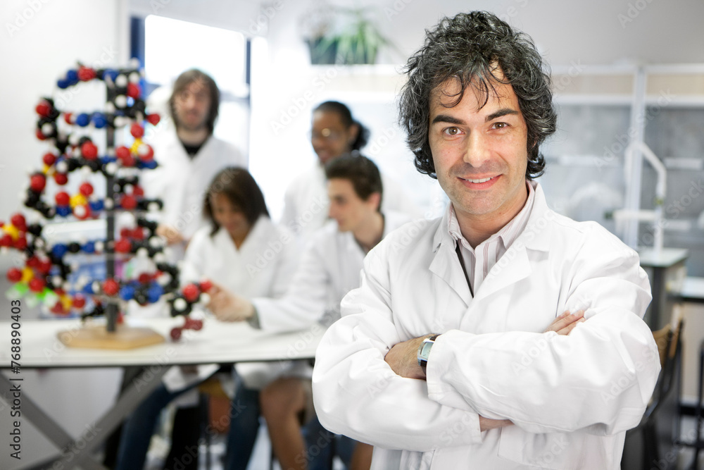 Biology Class. A science teacher in his native research laboratory environment with his students concentrating on their task in the background. Biology Class. A science teacher in his native research laboratory environment with his students concentrating on their task in the background.