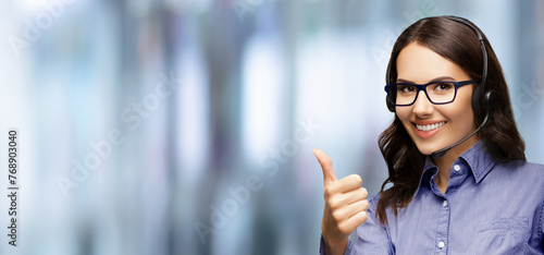 Contact Call Center Service. Customer support, sales agent. Caller advisor answer phone operator businesswoman in headset. Woman wear eye glasses spectacles show thumb up. Blurred office background