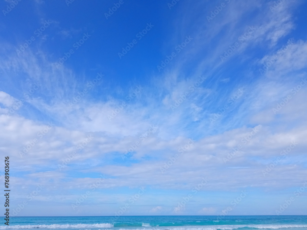 Bright blue sky with light clouds over the sea.