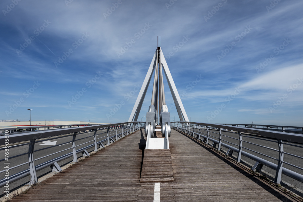Bridge with wooden pedestrian walkway floor with paint marks and metal braces to support the structure on a day with blue skies Bridge with wooden pedestrian walkway floor with paint marks and metal braces to support the structure on a day with blue skies