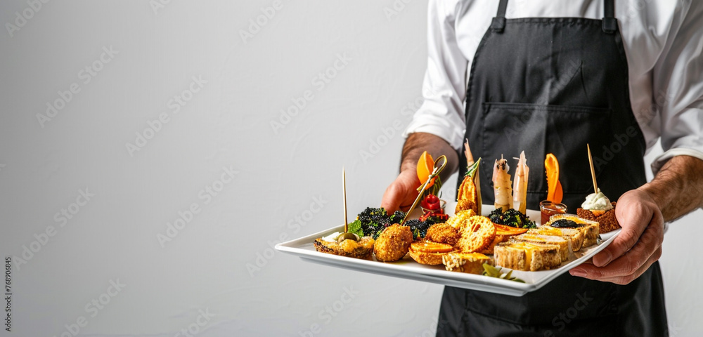 A friendly waiter in a smart apron and black attire, holding a tray of appetizing appetizers, each one a taste sensation, against a clean white background