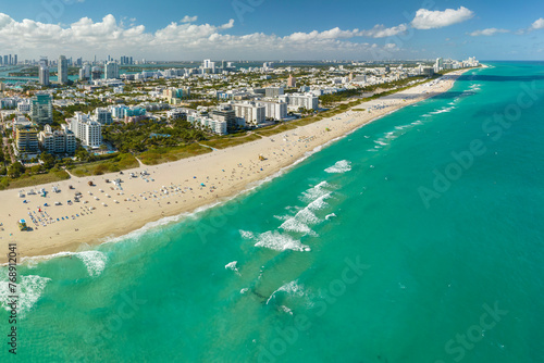 Travel destination in United States. South Beach sandy surface with tourists relaxing on hot Florida sun. Tourism infrastructure in southern USA. Miami Beach city with high luxury hotels and condos © bilanol