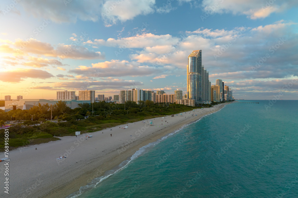 Fototapeta premium View from above of luxurious highrise hotels and condos on Atlantic ocean shore in Sunny Isles Beach city in the evening. American tourism infrastructure in southern Florida