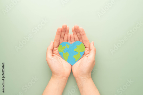 World heart day. Flat lay of hands holding heart shape with earth map made by paper on green background. Template for cardiology medical care, earth's day celebration, love and save the earth.