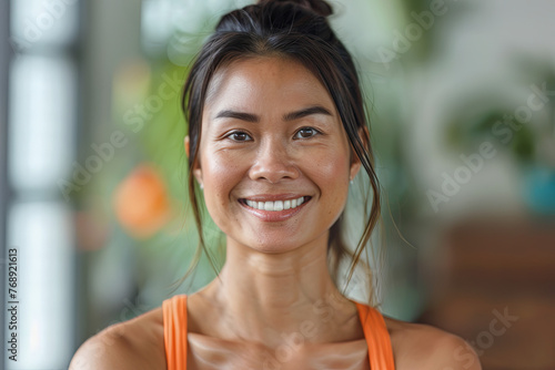 A smiling Thai yoga instructor in a studio setting, promoting wellness and fitness © Emanuel