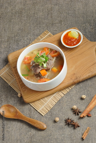 Bowl of meat soup on a wooden table