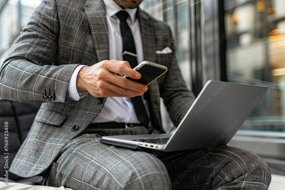 A businessman multitasking with a smartphone and laptop, embodying modern work habits A businessman multitasking with a smartphone and laptop, embodying modern work habits