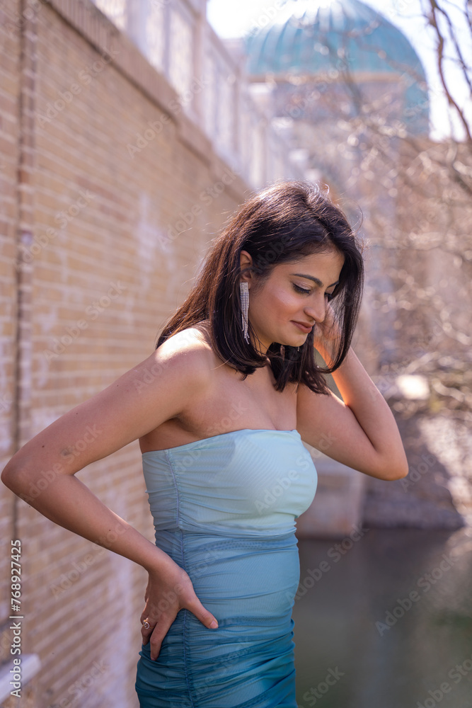 Fototapeta premium A woman in a blue dress is standing in front of a brick wall